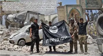  ??  ?? File photo shows a member of the Iraqi Counter-Terrorism Service (CTS) raising the victory gesture as others hold upside-down the black flag of the Islamic State (IS) group, outside the destroyed Al-Nuri Mosque in the Old City of Mosul, after the area was retaken from IS. — AFP photo