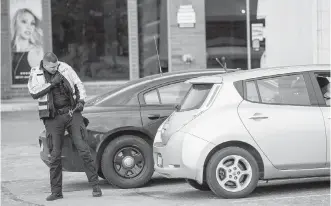  ?? DARREN STONE, TIMES COLONIST ?? Victoria police Const. Vlad Filatov radios in a licence-plate number for a distracted-driving infraction at a checkpoint on Blanshard Street.