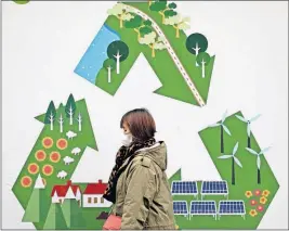  ?? [ANDY WONG/THE ASSOCIATED PRESS] ?? A woman wearing a mask against pollution walks past a poster promoting environmen­tal protection on a sidewalk in Beijing on Wednesday. The climate change conference COP24 is continuing in Katowice, Poland, through Friday.