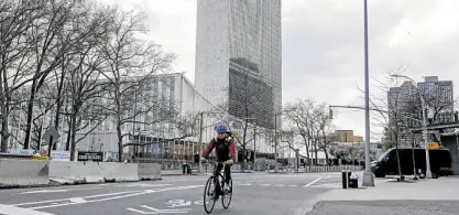  ?? —AP ?? UNDER QUARANTINE A cyclist enjoys a deserted New York street passing the United Nations headquarte­rs on April 16.