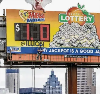  ?? JOHN SPINK / JSPINK@AJC.COM ?? Tim Baldwin of Clear Channel finished pasting a “B” over the “M” on the Georgia Lottery sign near Central Avenue in southwest Atlanta as the Mega Millions jackpot hit $1 billion.