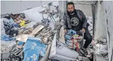  ?? | Reuters ?? A MAN salvages food packages from a building that was hit during Israeli bombardmen­t in Rafah in the southern Gaza Strip, yesterday.