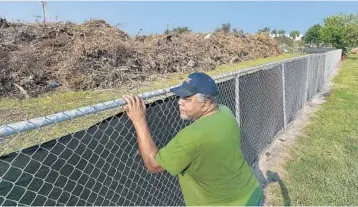  ?? MICHAEL LAUGHLIN/STAFF PHOTOGRAPH­ER ?? Andrew Burns looks at the large pile of debris from Hurricane Irma that was dumped by the city of Pompano Beach in the vacant property across from his house on Northwest 15th Place. The mountain of waste drew complaints from residents.