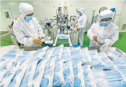  ?? THE ASSOCIATED PRESS FILE PHOTO ?? Workers pack masks at a factory in Suining, China, in February. Chinese exporters have benefited from global demand for masks and medical supplies.