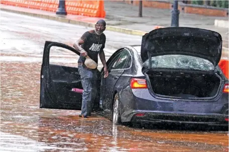  ?? AP PHOTO/JOHN BAZEMORE ?? On Sept. 14, Bernard Johnson retrieves belongings from his flooded rental car in downtown Atlanta.