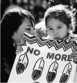  ?? Ted Rhodes / Calga ry Herald ?? Wynter Ducharme and her daughter Rayne hold a placard as they listen during the Sisters In Spirit ceremony for mis
sing and murdered aboriginal women in Calgary.