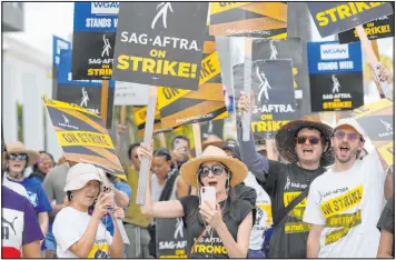  ?? Chris Pizzello The Associated Press file ?? People picketing on behalf of the Screen Actors Guild-american Federation of Television and Radio Artists carry signs outside Netflix in Los Angeles on Sept. 27.