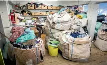  ??  ?? Clothing piled high in sacks from charity bins is dealt with on the sorting floor.