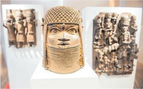  ?? FOTO: DANIEL BOCKWOLDT/DPA ?? Drei Raubkunst-Bronzen aus dem Benin in Westafrika sind im Hamburger Museum für Kunst und Gewerbe in einer Vitrine ausgestell­t.