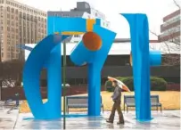  ?? STAFF PHOTO BY DOUG STRICKLAND ?? A pedestrian passes the sculpture “Volumes” by Jim Collins at the intersecti­on of 11th and Chestnut streets downtown on Tuesday.