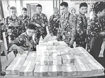  ?? — AFP photo ?? Con scated cash and cheques amounting to US$1.6 million are shown by Philippine military personnel during a press conference in this  le photo at the provincial capital of Marawi City.