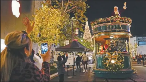  ?? (AP/Ashley Landis) ?? Santa Claus waves to shoppers from a safe distance at the top level of a trolly at The Grove shopping center in Los Angeles. Santa visits were canceled due to the spread of covid-19.