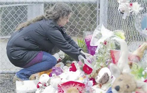  ?? PHIL CARPENTER / MONTREAL GAZETTE ?? Martine Gaudet places a stuffed toy against a fence near the site where the remains of Cédrika Provencher were
found on Saturday in a wooded area on the edge of Highway 40 in St-Maurice, east of Trois-Rivières, Que.