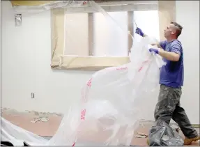  ?? Keith Bryant/The Weekly Vista ?? Bella Vista Fire Department Battalion Chief Robert Hamilton tears plastic off the ceiling after a long day of painting in the Bella Vista Fire Department’s training room.