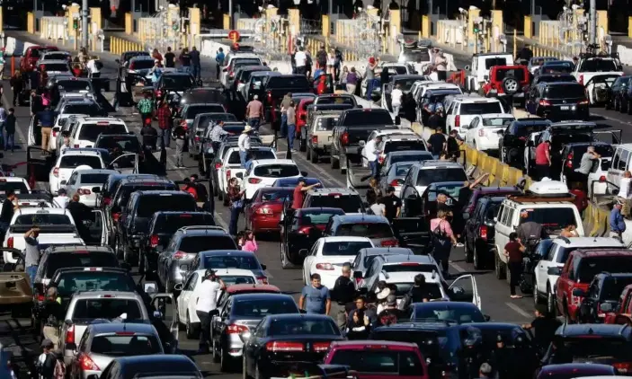  ??  ?? People attempting to cross into the US look on by their vehicles during a temporary closure of the San Ysidro port of entry on 25 November 2018 in Tijuana, Mexico. Photograph: Mario Tama/Getty Images