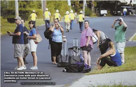  ?? STAFF PHOTO BY NICOLAUS CZARNECKI ?? CALL TO ACTION: Members of an Eversource crew walk past displaced residents on Cutler Street in Lawrence yesterday.