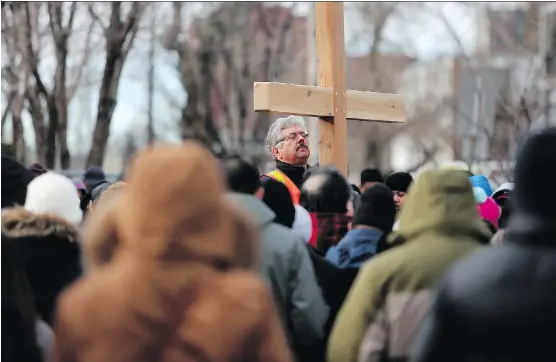 ?? PHOTOS: LEAH HENNEL ?? Participan­ts carry the cross during the Way of the Cross on Good Friday. They paused at 14 symbolic stations in downtown Calgary.