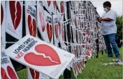  ?? BEN GRAY/FOR THE AJC ?? Catolyn Merriweath­er, whose mother JoeAnn Snead died from COVID-19 in April, helps hang 5,000 broken hearts on the fence outside of the National Museum for Civil and Human Rights in Atlanta on Aug. 27, as part of the “Loved Ones, Not Numbers” campaign to humanize the toll of the current pandemic.