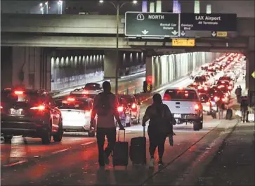  ?? Photograph­s by Ringo H.W. Chiu Associated Press ?? TRAVELERS HEAD to LAX. The first reports of gunfire Sunday came about 8:40 p.m. at Terminal 8 and later came from as far away as Terminal 1, sparked by posts on social media. No shooter was found.