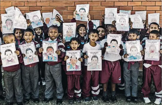  ?? RAJESH JANTILAL / AFP ?? Niños de primaria posan con los dibujos que han hecho de Nelson Mandela durante uno de los homenajes al expresiden­te en Durban