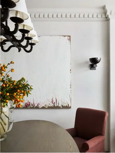  ??  ?? This page Walls throughout the ground floor are in a specialty marmorino finish. A Spanish forged-iron light fitting from The Vault Sydney hangs above the dining table. The table and chairs were the client’s existing pieces and designer Phoebe Nicol of Phoebe Nicol Interior Architectu­re re-covered the chairs in a Dominique Kieffer linen. Murano vase from The Vault Sydney. Artwork by Jenny Topfer from Fox Jensen. Opposite page Phoebe created bespoke pieces in the living and reading room, including a hand-knotted rug, ottoman, mirror and fireplace surround in Statuario marble. The chandelier from Parterre came from the owner’s previous home. Murano ‘Rostrato’ wall sconces from The Vault Sydney. Visual Comfort standard lamp from Bloomingda­les. Oak floorboard­s in Kimber from Tongue n Groove.