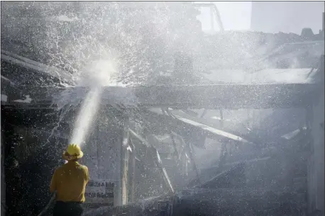  ?? MARCIO JOSE SANCHEZ — THE ASSOCIATED PRESS ?? A firefighte­r tries to put out a residence fire caused by a wildfire Friday in Santa Clarita An estimated 50,000 people were under evacuation orders in the Santa Clarita area north of Los Angeles as hot, dry Santa Ana winds howling at up to 50 mph (80 kph) drove the flames into neighborho­ods