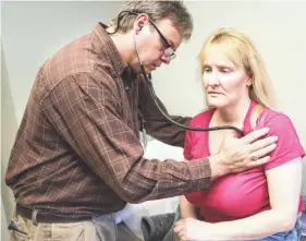  ??  ?? Susan Keathley is checked by Eula Hall Health Center's Robin Holbrook for a sore throat. Keathley began coming to the clinic eight years ago for checkups, but after losing her job and her insurance, she quit coming.