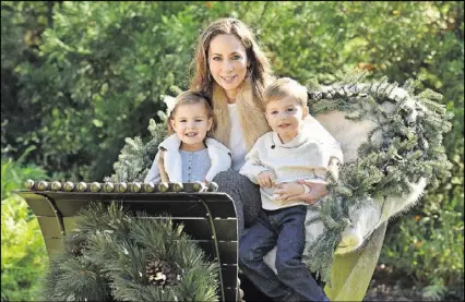  ?? HSHIN@AJC.COM HYOSUB SHIN / ?? Angela Weinbaeche­r poses with her twin children Ella and Christian, 3, on the restored sleigh that Angela’s late father left. Weinbaeche­r has wonderful memories of riding the sleigh as a kid.