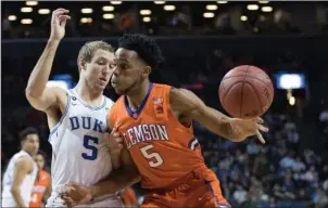  ?? The Associated Press ?? DUKE’S UP: Duke guard Luke Kennard, left, defends against Clemson forward Jaron Blossomgam­e during the first half of an Atlantic Coast Conference tournament game Wednesday in Brooklyn, N.Y. Kennard made two key jumpers in the final 2:04 as the...