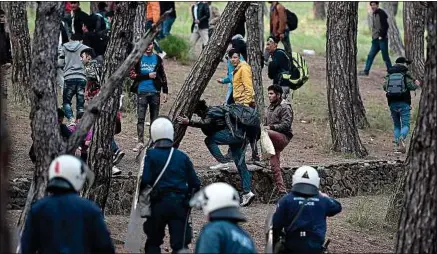  ??  ?? Des migrants fuient la police, sur l’île de Lesbos, mardi, alors qu’ils espéraient prendre un ferry pour Athènes.