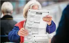  ?? Steve Marcus/Associated Press ?? An election worker inspects a mail-in ballot in the count room at the Clark County Election Department in North Las Vegas.