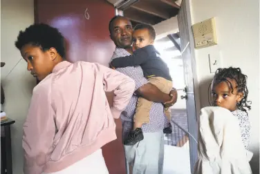  ?? Photos by Scott Strazzante / The Chronicle ?? Eritrean refugee Efrem Asefaw holds son Yafet, 2, as daughters Delina, 11, and Betal, 5, wait to head to a park near their current quarters. Earlier, they had a short stay at the Airbnb condo of Sefani Tadesse.