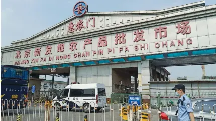  ?? (Reuters) ?? A POLICE OFFICER is seen outside an entrance of the Xinfadi wholesale market, which has been closed for business after new coronaviru­s infections were detected, in Beijing yesterday.