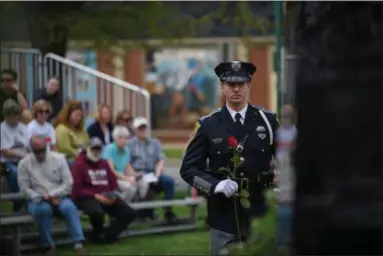  ?? ERIC BONZAR — THE MORNING JOURNAL ?? Lorain police Officer Eric Alten places a red rose at the base of the Wellington Safety Forces Memorial in honor of a fallen officer May 10, during the Lorain County Police Memorial at Howk Memorial Park in Wellington.