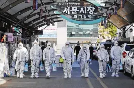  ?? IM HWA-YOUNG/ AP ?? Workers wearing protective gears spray disinfecta­nt as a precaution against the COVID-19 at a local market in Daegu, South Korea, on Sunday. South Korea’s president has put the country on its highest alert for infectious diseases and says officials should take “unpreceden­ted, powerful” steps to fight a viral outbreak.