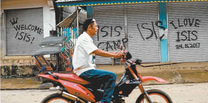  ??  ?? Shuttered shopfronts sprayed with proDaesh graffiti in Marawi, on the Philippine island of Mindanao this month.