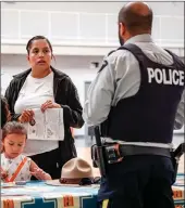  ?? JEFF MCINTOSH/The Canadian Press ?? Potential recruits talk with an RCMP officer at a Blood Tribe Police Service hosted recruiting drive held last week in Stand Off, Alta.