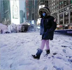  ?? RICHARD DREW/AP ?? A girl kicks at snow in New York’s Times Square on Friday. A winter storm that left areas of the South with more than 6 inches of snow moved into the Northeast and prompted many schools to close.