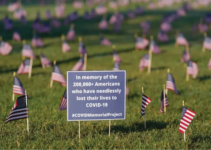  ??  ?? Activists from the COVID Memorial Project mark the deaths of 200,000 lives lost in the U.S. to COVID-19 after placing thousands of small American flags places on the grounds of the National Mall in Washington, yesterday. Photo: AP