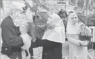  ??  ?? A man dressed as Santa Claus speaks to Russian nuns as they hold Christmas trees distribute­d by the municipali­ty at Jaffa Gate in Jerusalem’s Old City.