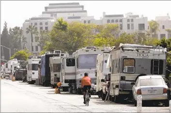  ?? Genaro Molina Los Angeles Times ?? rides past a line of recreation­al vehicles and cars that serves as a homeless encampment near Ballona Creek in Marina del Rey on May 24, 2022.