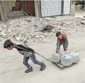  ??  ?? A child pulls a crate carrying water bottles in the once opposition-held Shaar neighborho­od in the northern Syrian city of Aleppo. (AFP)