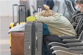  ?? AP PHOTO BY ALEX BRANDON ?? Jessica Andrijausk­as, from Buenos Aires, rests her head on her luggage as she awaits the results of her COVID-19 test, at Ronald Reagan Washington National Airport, Wednesday, Dec. 29 in Arlington, Va.