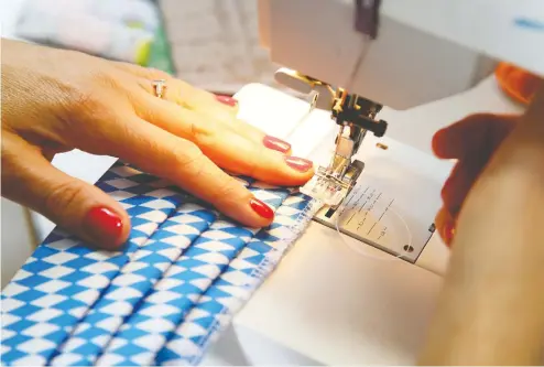  ?? ALEXANDER HASSENSTEI­N / GETTY IMAGES ?? The need for masks has prompted a run on sales of sewing machines, and sparked others to put old machines back into use.