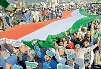  ?? — PTI ?? Farmers hold a tricolor to protest against the new farm laws at Ghazipur in New Delhi on Sunday.