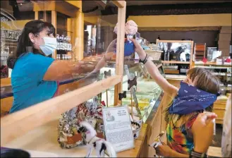  ?? FILE PHOTO ?? Manager Evelyn Espinoza serves customers July 28 at Rocky Mountain Chocolate Factory on Taos Plaza. ‘This is like my second home,’ said Espinoza, who has been working at the business for 20 years. Owner Bowe Ellis closed the store over the summer due in part to the loss of revenue during COVID-19 restrictio­ns.