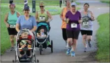  ??  ?? A group of women, including some pushing strollers, run along the Schuylkill River Trail in Pottstown as part of a 5K race held at Riverfront Park.