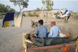  ?? ?? CHILLING OUT. Villagers cool off beside a donkey-driven fan during a heatwave in Jacobabad.