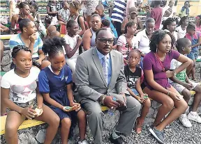  ??  ?? Mayor of Port Antonio Paul Thompson is seated with a group of children during a Christmas treat on Wednesday.