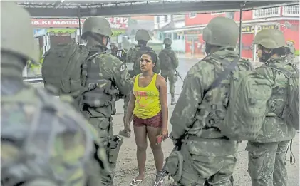  ?? EFE ?? Documentos. Una patrulla revisa los papeles de identidad de una mujer en una de las favelas allanadas.